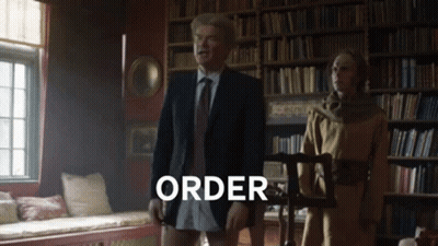Man In Suit And Tie In Front Of Bookshelf Saying Order GIF