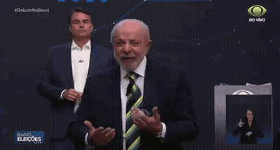 Man In Suit And Tie In Front Of Debate Screen GIF