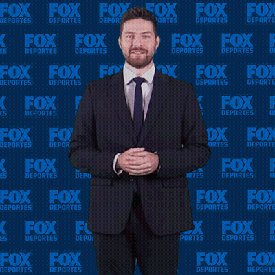 Man In Suit And Tie In Front Of Fox Deportes Background GIF