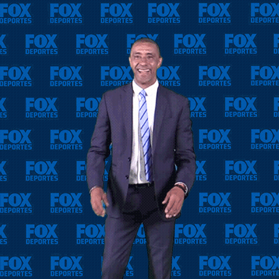 Man in Suit and Tie in Front of Fox Deportes Wall