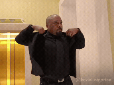 Man In Suit And Tie In Front Of Gold Elevator GIF