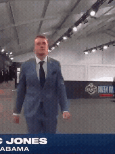 Man in Suit and Tie in Front of Jones Abama Banner