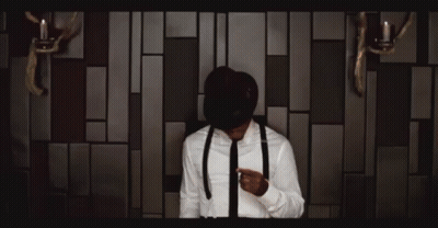 Man In Suit And Tie In Front Of Light Bulb Wall GIF