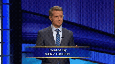 Man In Suit And Tie In Front Of Merv Griffin Sign GIF