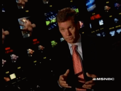Man in Suit and Tie in Front of MSNBC Screens
