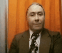 Man In Suit And Tie In Front Of Orange Curtain GIF