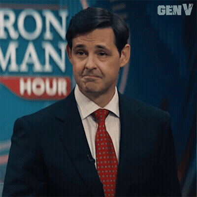 Man In Suit And Tie In Front Of Ron Man Hour Sign GIF