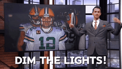 Man In Suit And Tie In Front Of Screen Saying Dim The Lights GIF
