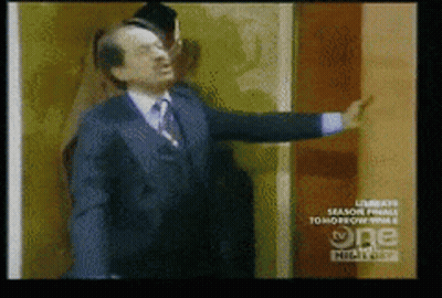Man In Suit And Tie In Front Of TV Wall GIF