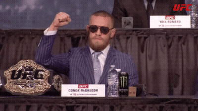 Man In Suit And Tie In Front Of UFC Sign GIF