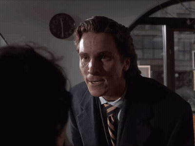 Man In Suit And Tie In Front Of Wall Clock Showing Almost 5:00 GIF