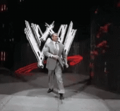 Man In Suit And Tie In Front Of WWE Logo GIF