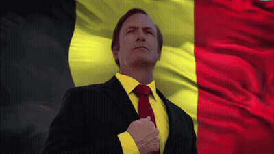 Man In Suit And Tie In Front Of Yellow And Red Flag GIF