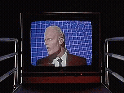 Man In Suit And Tie Laughing On TV GIF