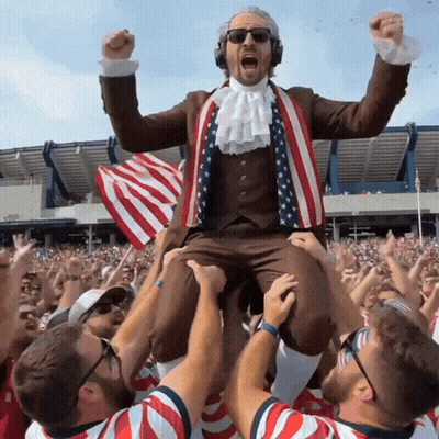Man In Suit And Tie Lifted By Crowd GIF