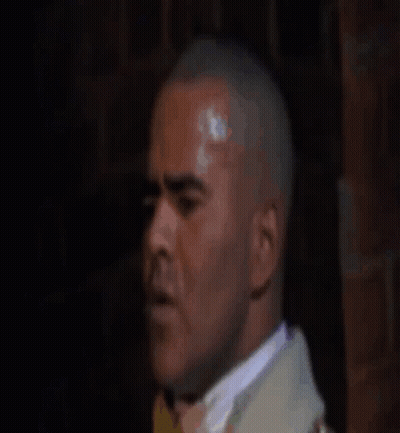 Man In Suit And Tie Looking At Camera In Dark Room GIF