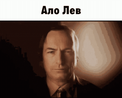Man In Suit And Tie Looking At Camera Says Alo Lev GIF