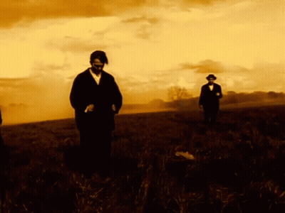 Man In Suit And Tie Looks At Camera In Dark GIF