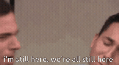 Man In Suit And Tie Saying I'm Still Here, We're All Still Here GIF