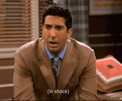 Man In Suit And Tie Shocked On Couch GIF