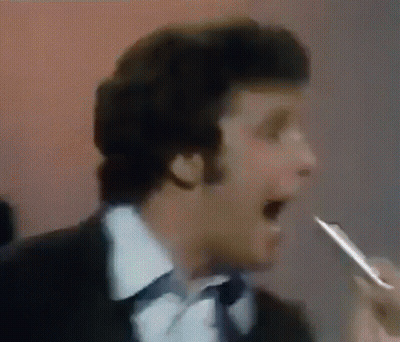 Man In Suit And Tie Singing Into Microphone Holding Pen GIF