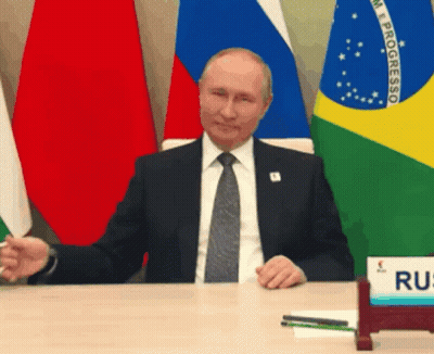 Man In Suit And Tie Sitting At Desk With Progresso Flags GIF