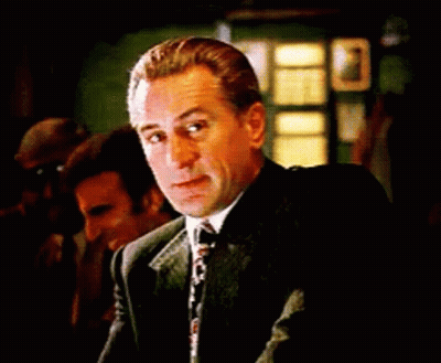 Man In Suit And Tie Sitting At Table Looking At Camera GIF