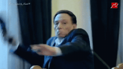 Man In Suit And Tie Sitting At Table With Hands Outstretched GIF