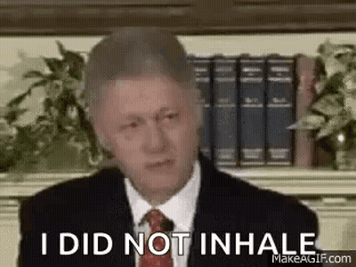 Man In Suit And Tie Sitting Before Bookshelf GIF