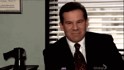 Man In Suit And Tie Sitting By Window With Blinds GIF