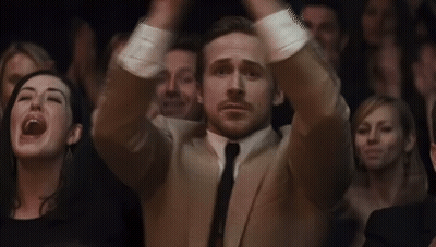 Man In Suit And Tie Sitting In Crowd GIF