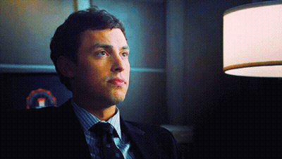 Man In Suit And Tie Sitting In Dark Room GIF