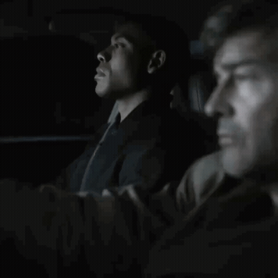 Man In Suit And Tie Sitting In Dark Room GIF