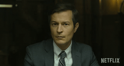 Man In Suit And Tie Sitting In Front Of Netflix Sign GIF