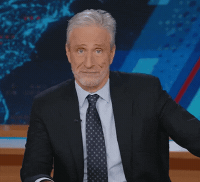 Man In Suit And Tie Sitting In Front Of Screen GIF