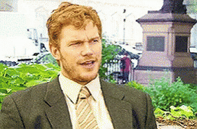 Man In Suit And Tie Sitting In Front Of Statue GIF