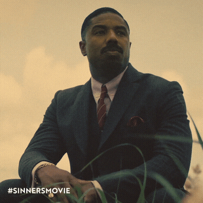 Man In Suit And Tie Sitting In Grass With #Sinnersmovie GIF