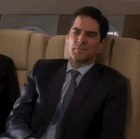 Man In Suit And Tie Sitting In Plane Chair GIF