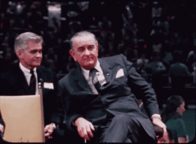 Man In Suit And Tie Sitting In Stadium GIF