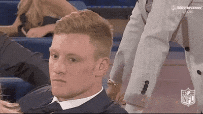 Man In Suit And Tie Sitting In Stadium With NFL Logo GIF
