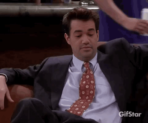 Man In Suit And Tie Sitting On Couch Looking At Camera GIF