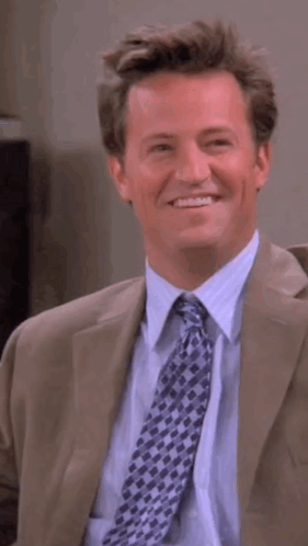 Man In Suit And Tie Smiling And Looking To Side GIF