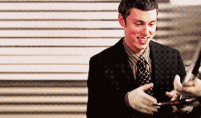 Man In Suit And Tie Smiling Holding Something GIF