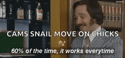 Man in Suit and Tie Smiling in Front of Bookshelf With Snail