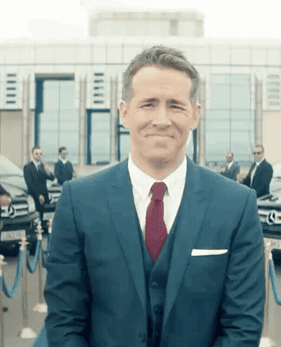 Man In Suit And Tie Smiling In Front Of Building GIF
