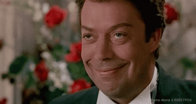 Man In Suit And Tie Smiling In Front Of Red Roses GIF