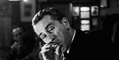 Man In Suit And Tie Smoking Cigarette In Bar GIF
