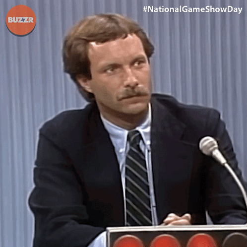 Man In Suit And Tie Speaking Into Microphone With Buzzr GIF