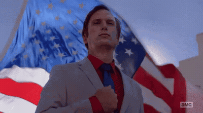 Man In Suit And Tie Standing Before American Flag GIF