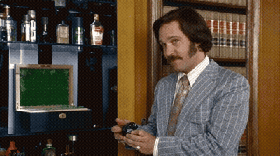 Man In Suit And Tie Standing Before Bookshelf GIF